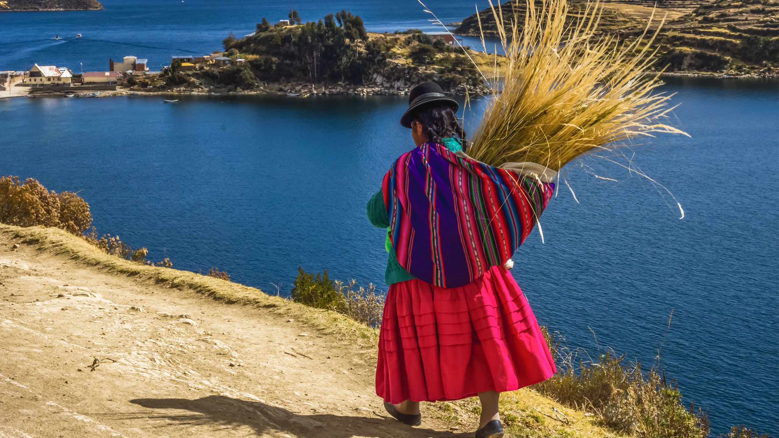 Bolivianisches Altiplano aus dem Reiseprospekt: Indígena auf der Sonneninsel im Titicaca-See mit einem Büschel des berühmten Totora-Schilfs. | NiarKrad, Shutterstock